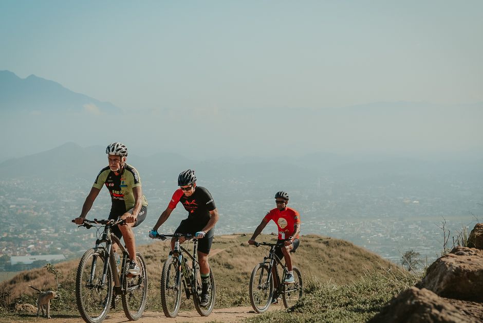 Men cycling on a mountain trail with scenic city view backdrop. Perfect for fitness, adventure, and outdoor themes.
