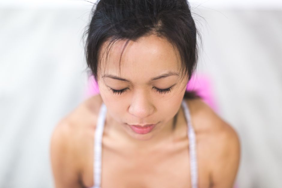 A young woman meditating indoors, focusing on relaxation and mindfulness.