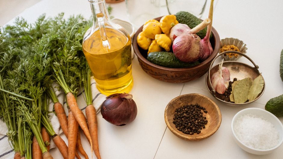 Assorted fresh vegetables and spices on a kitchen table ready for cooking.