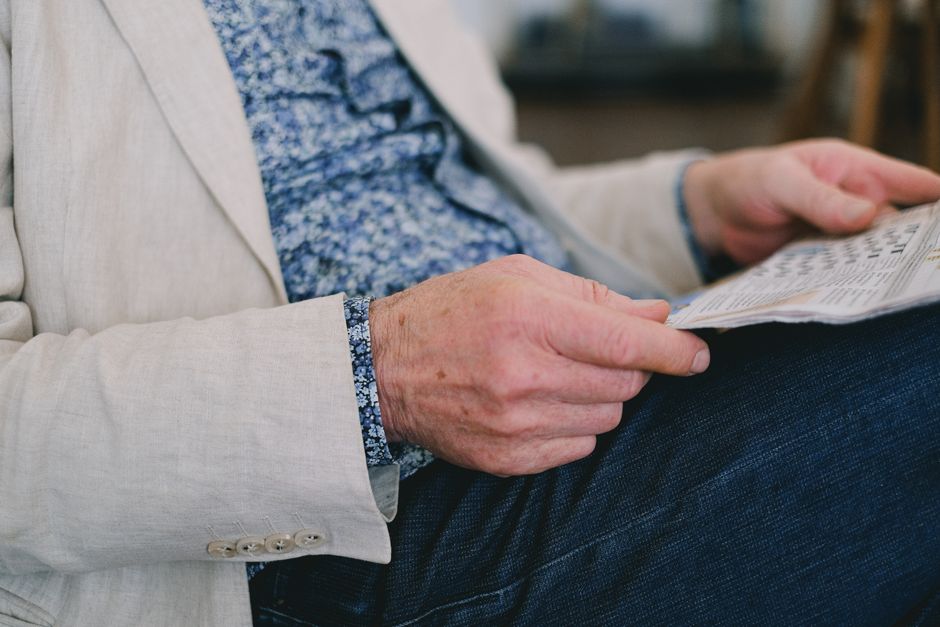 Close-up of a senior adult's hand holding a newspaper in a calm setting.