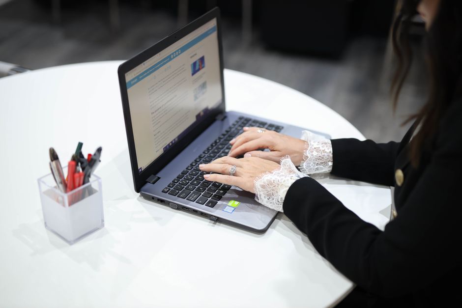 A woman typing on a laptop in a contemporary office setting, showcasing technology and efficiency.