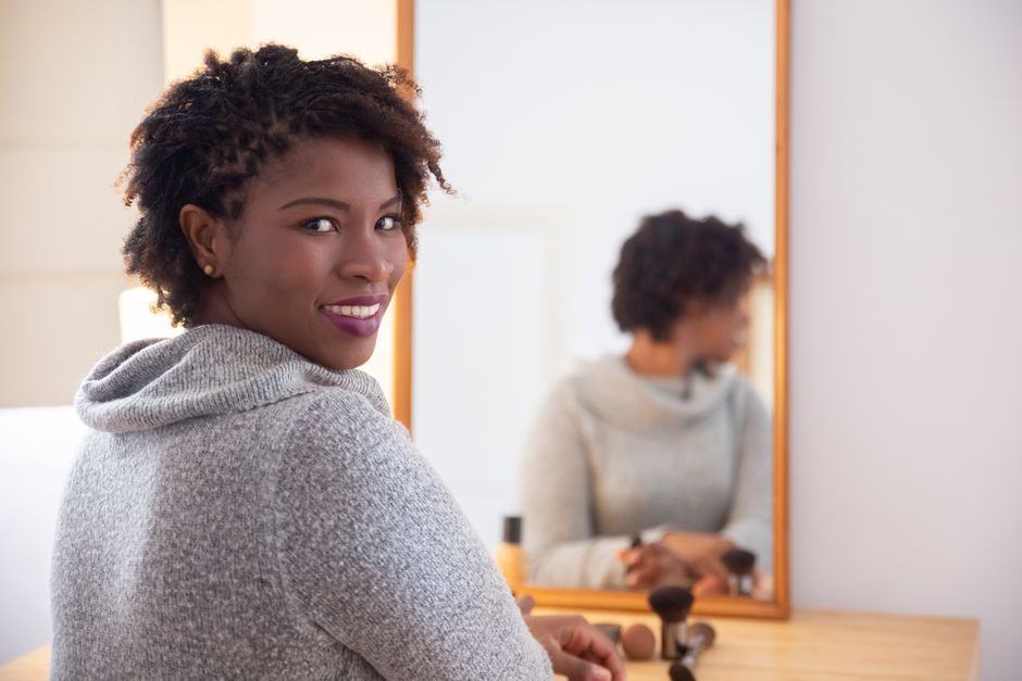 A woman enjoys a joyful moment in front of a mirror, reflecting confidence and beauty.