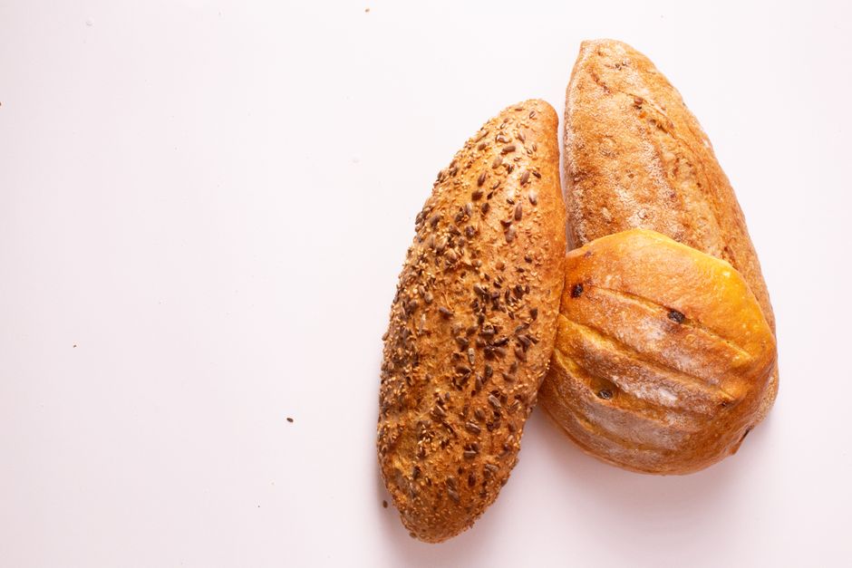 Top view of three freshly baked artisan bread loaves with seeds and crusty surfaces.