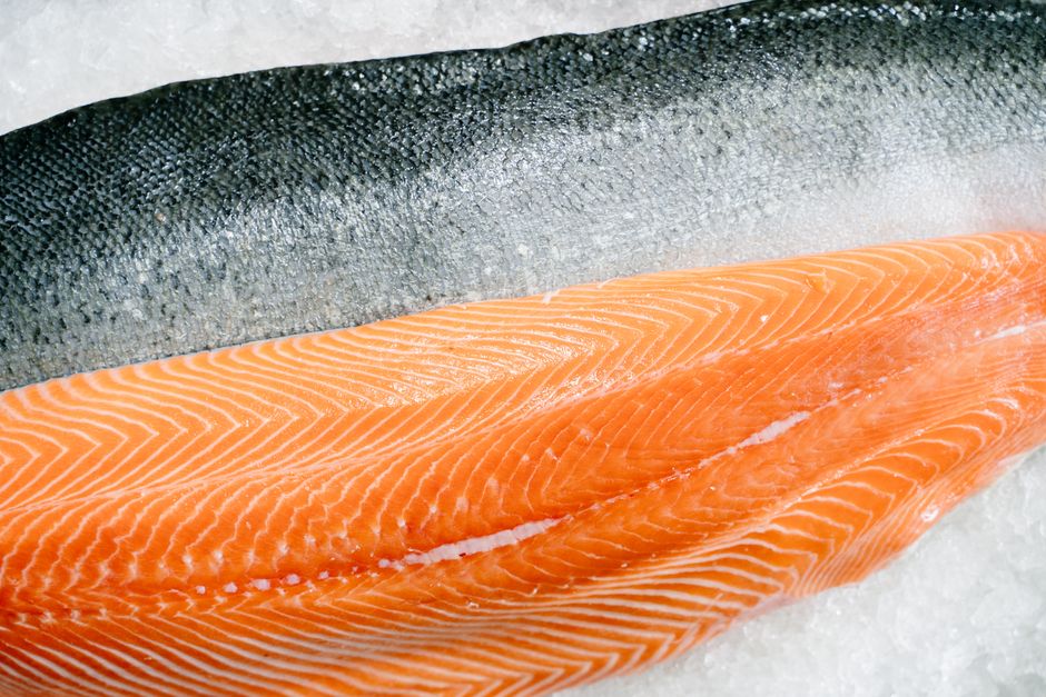 Detailed close-up of a fresh raw salmon fillet with skin on ice, highlighting texture and freshness.