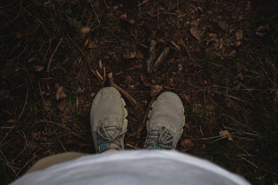 A pair of grey sneakers on a woodland path, offering an earthy outdoor perspective.