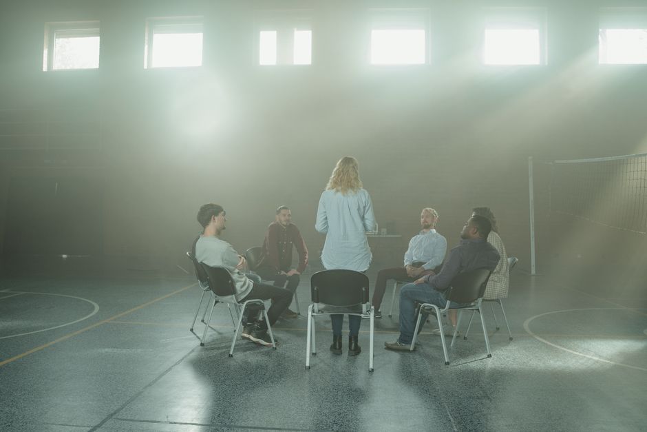 A group therapy session with diverse adults seated in a sunlit room.