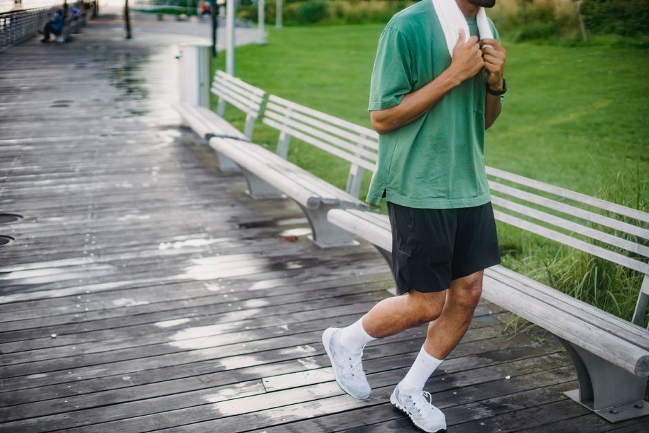A man in a green shirt goes for a jog on a wooden boardwalk, promoting a healthy lifestyle.