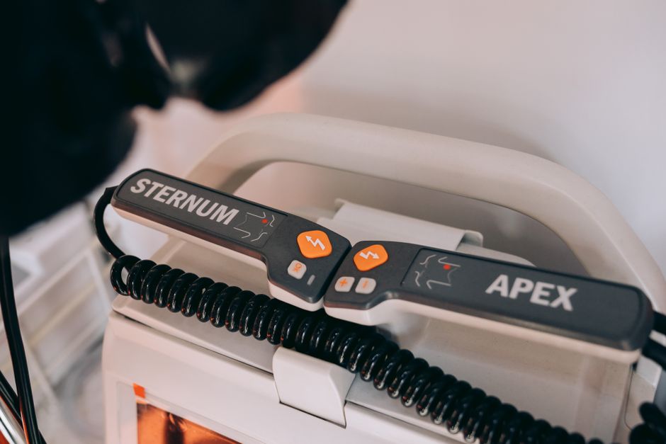 Detailed view of a defibrillator with labeled sternum and apex paddles.