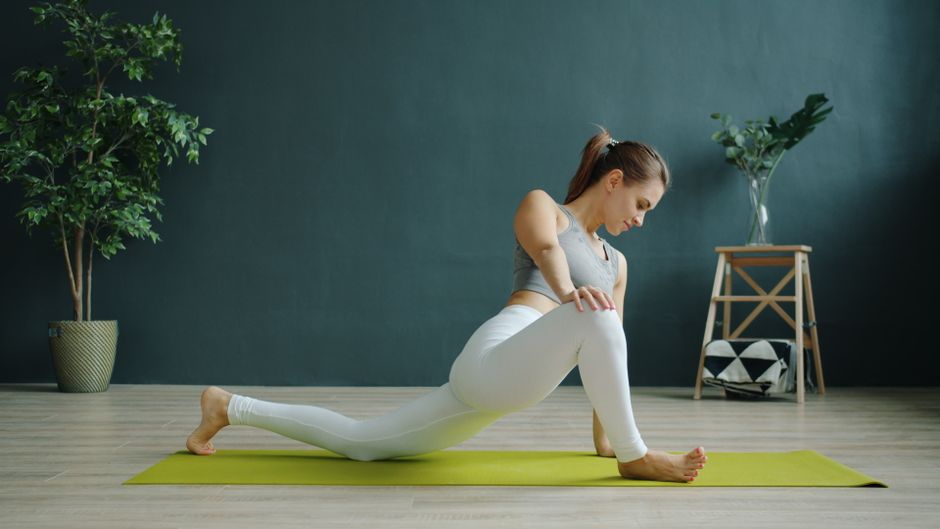 A woman performs a yoga stretch indoors, enhancing flexibility and mindfulness.